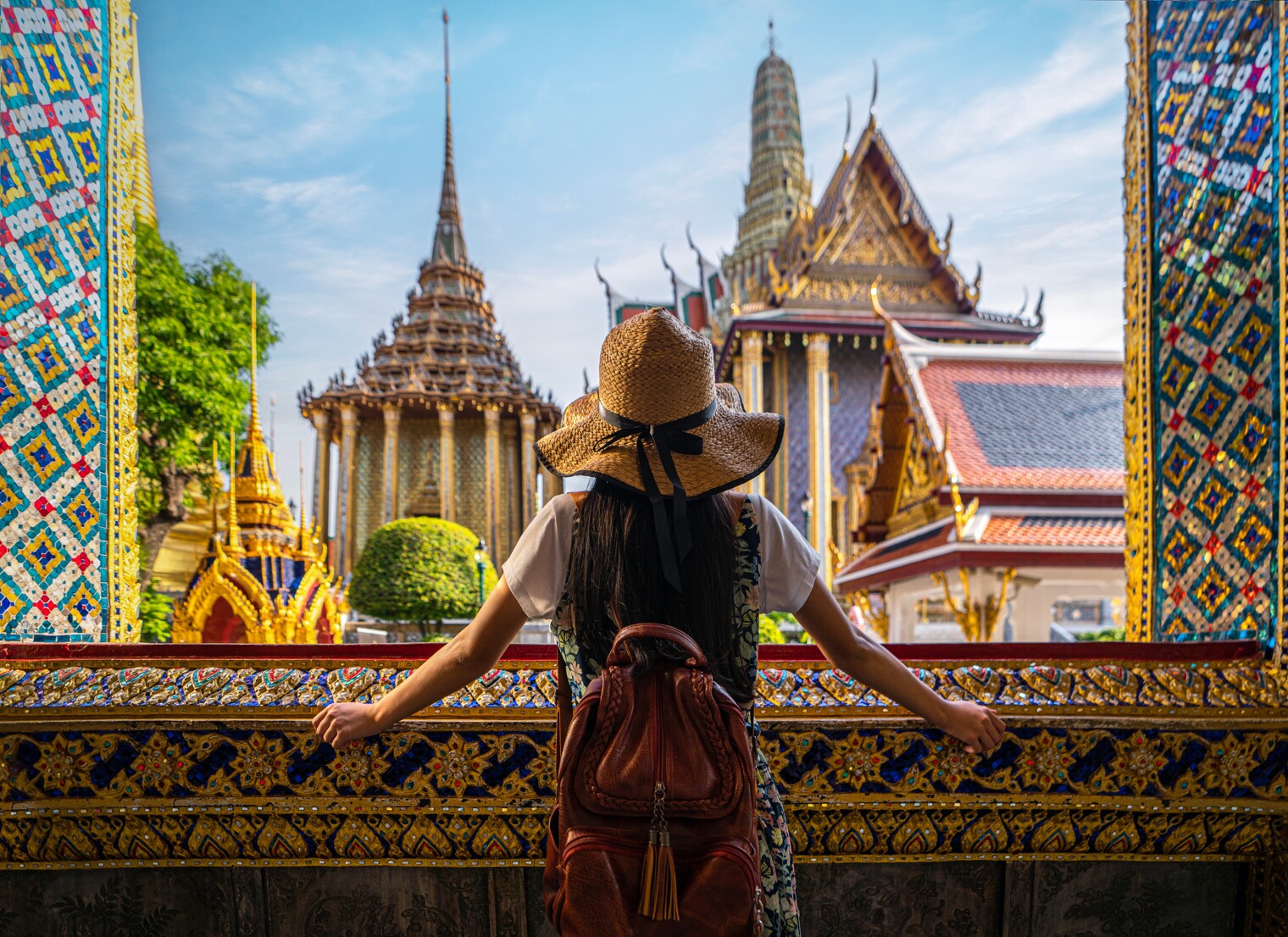Une femme de dos en train d'admirer des temples thaïlandais