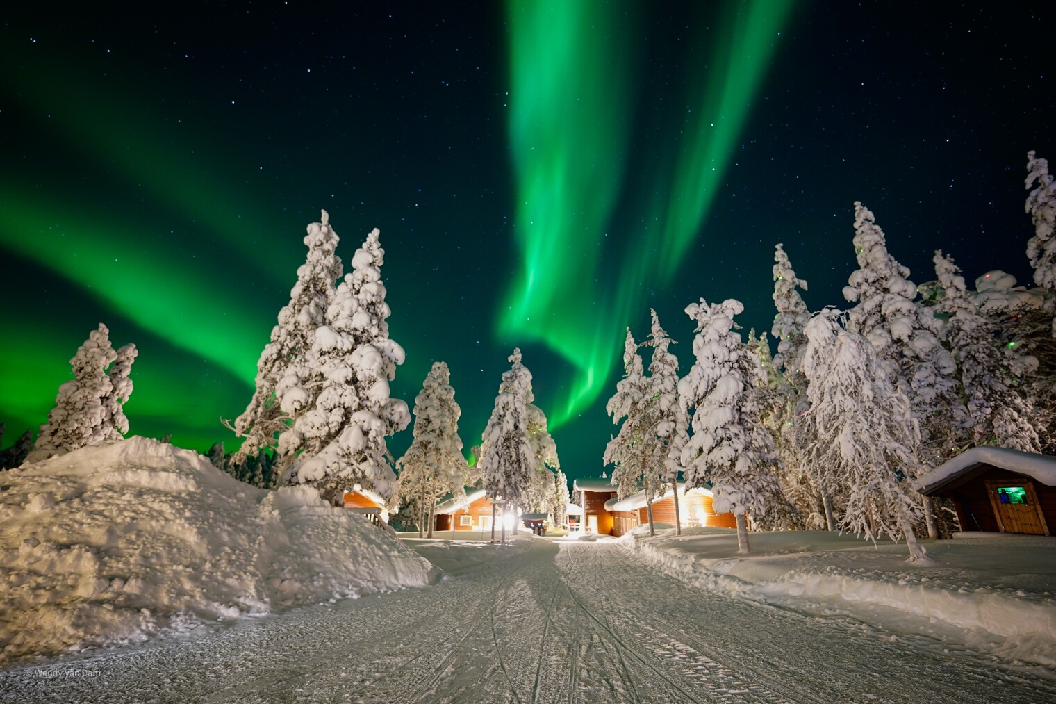 Paysage enneigé de Laponie avec des chalets et des aurores boréales