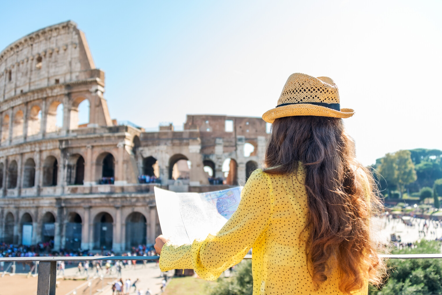 Une femme en train de regarder un plan de Rome face au Colisée