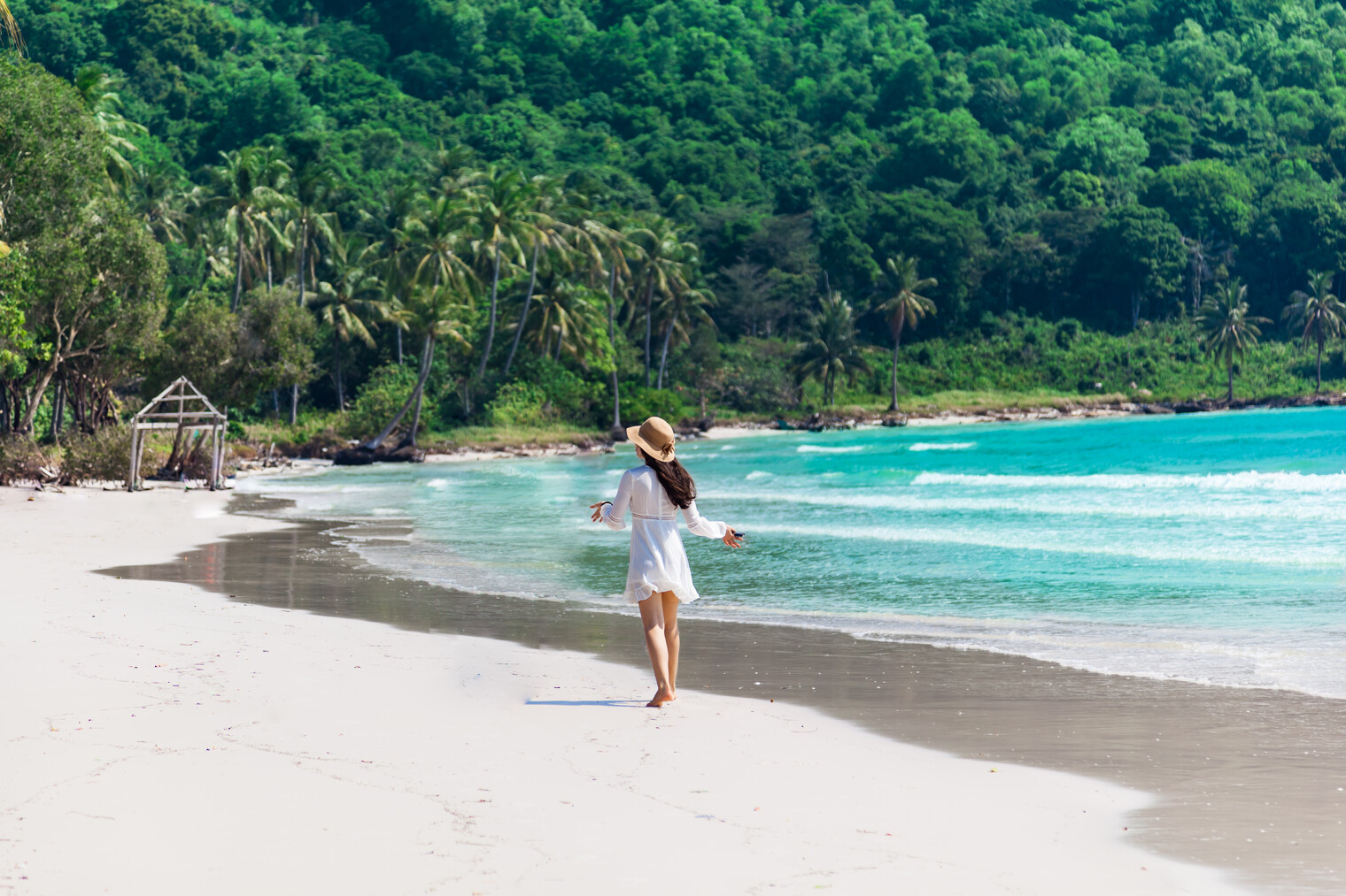 Une femme seule marchant sur une belle plage paradisiaque bordée par les palmiers