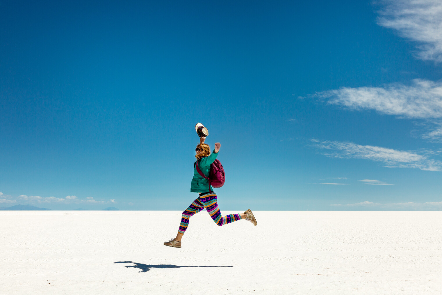 Une femme en train de sauter en l'air dans le désert de Uyuni en Bolivie