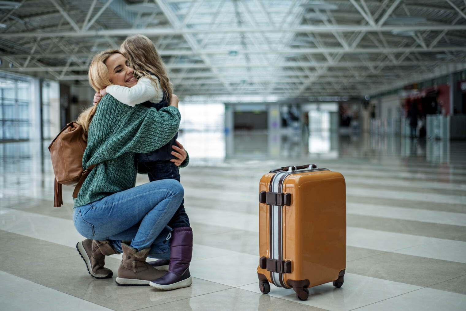 Une maman à l'aéroport prenant sa fille dans les bras