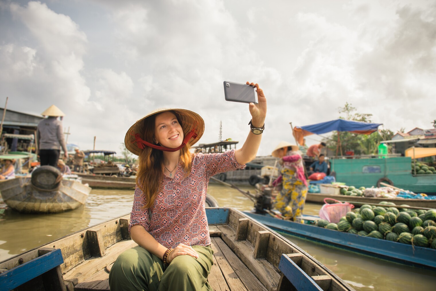 Une femme en train de prendre un selfie sur le marché flottant de Cai Rang au Vietnam