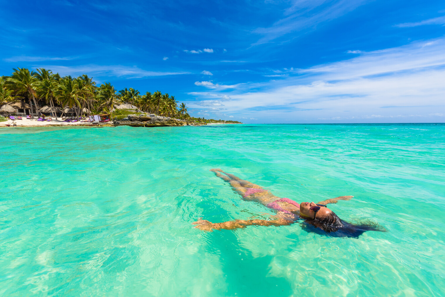 Femme dans l'eau turquoise face à la plage de Tulum au Mexique
