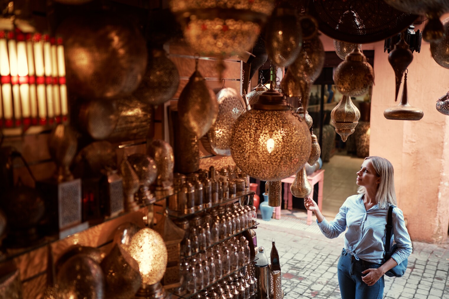 Une femme en train de regarder des lustres marocains dans un souk