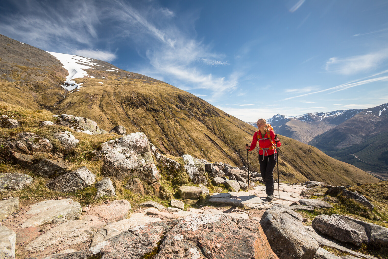 Une femme en train de randonner dans la montagne avec des bâtons de marche