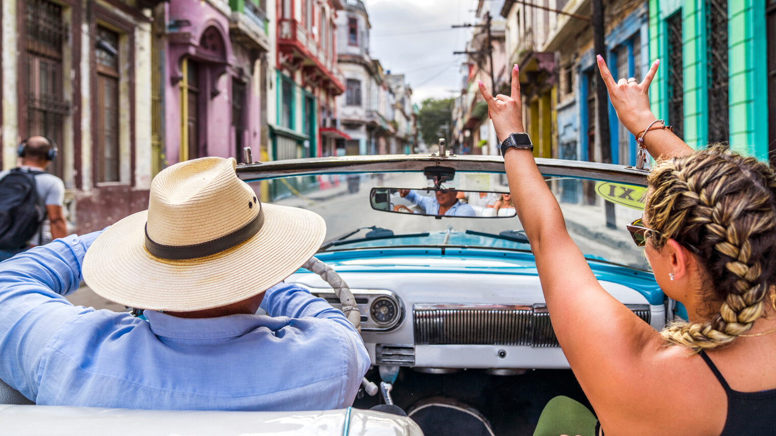 Une femme de dos dans une voiture ancienne en plein coeur de La Havane à Cuba