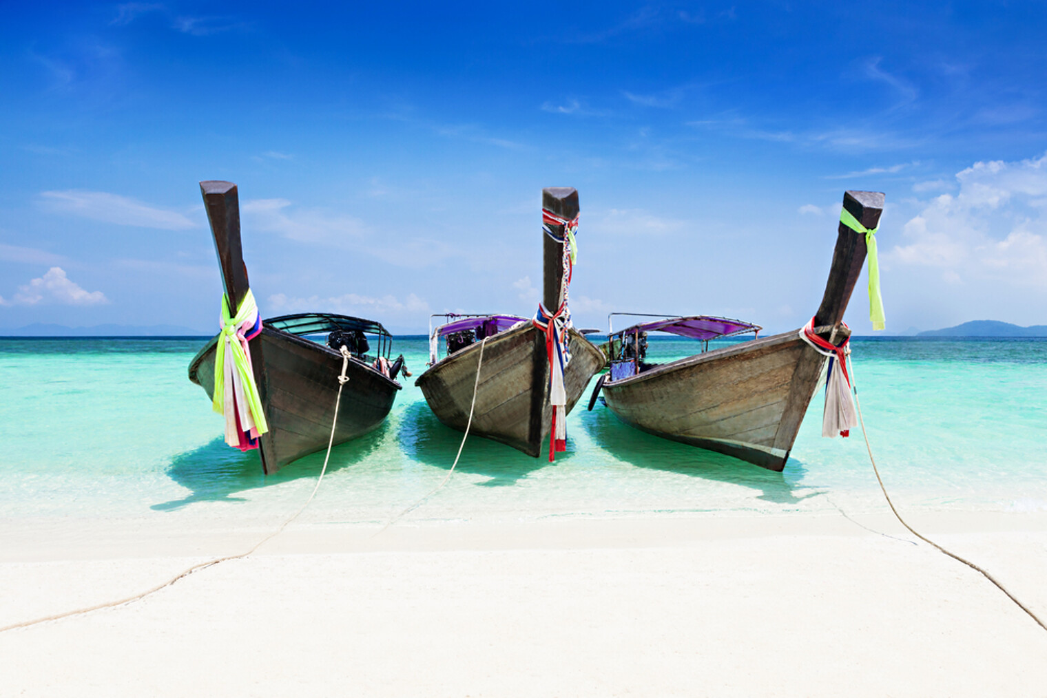 3 bateaux long tails sur une plage sable blanc en Thaïlande