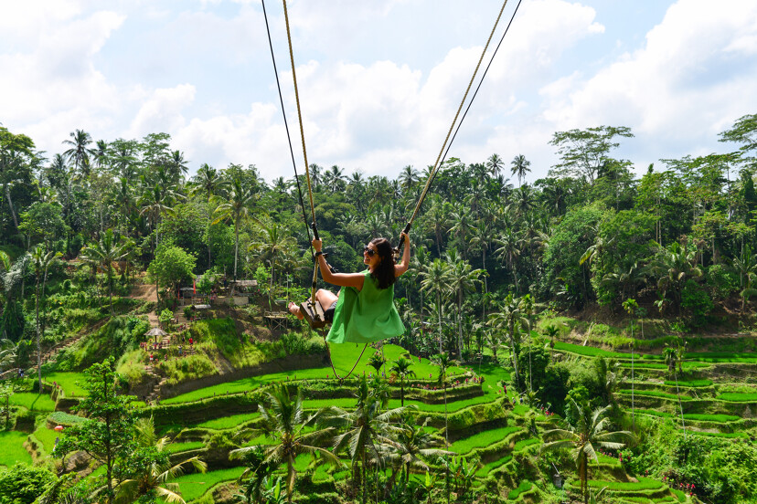 Une femme de dos en train de faire de la balançoire face aux rizières en terrasse à Ubud à Bali