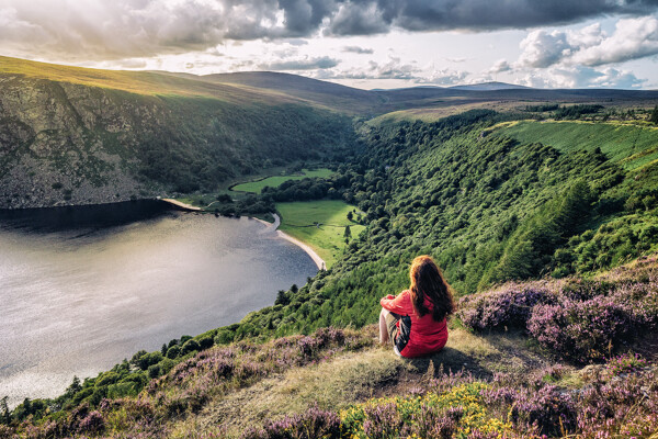 Une femme en voyage assise face à un lac de montagne