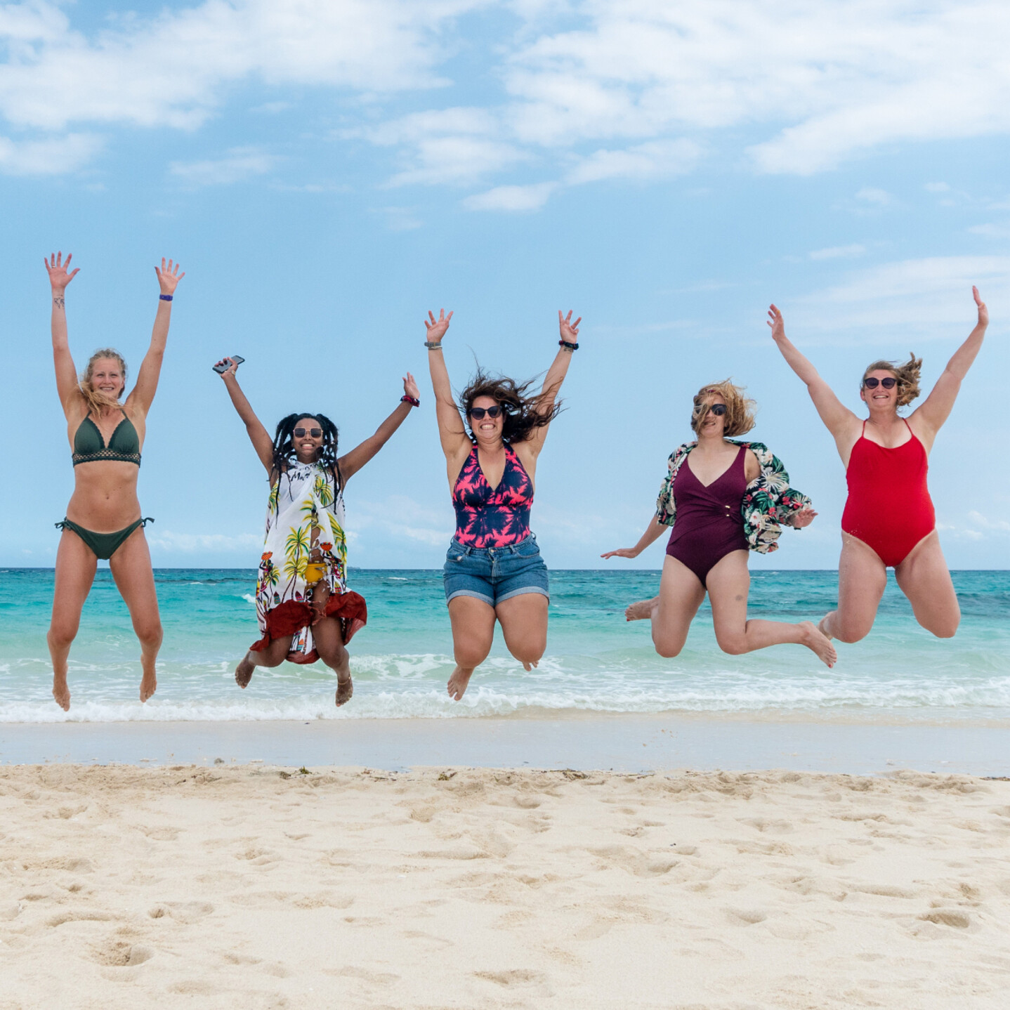 Cinq femmes en plein saut sur la plage