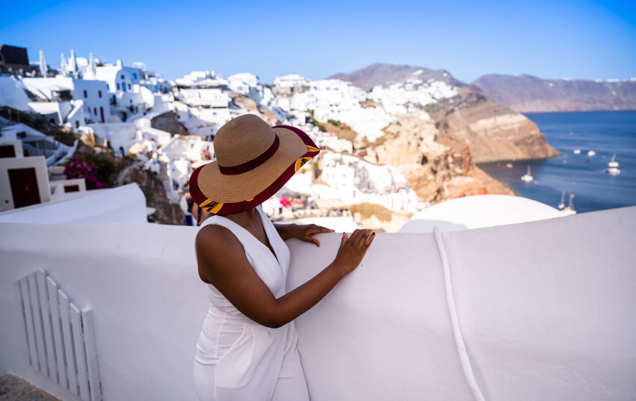 Une femme de copines de voyage qui contemple la mer devant un muret blanc à Santorin